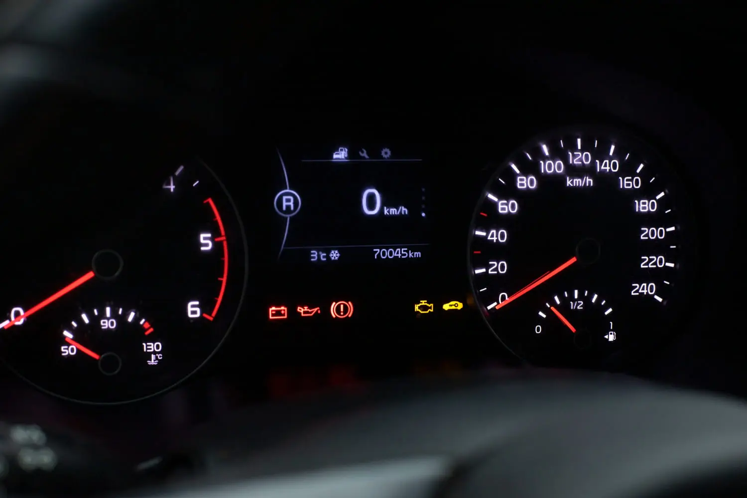Illuminated car dashboard instrument cluster featuring an active yellow check engine light and warning indicators.
