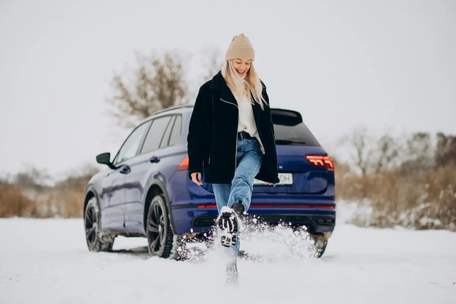 Car driving through winter snow highlights the need for cold-weather prep steps.