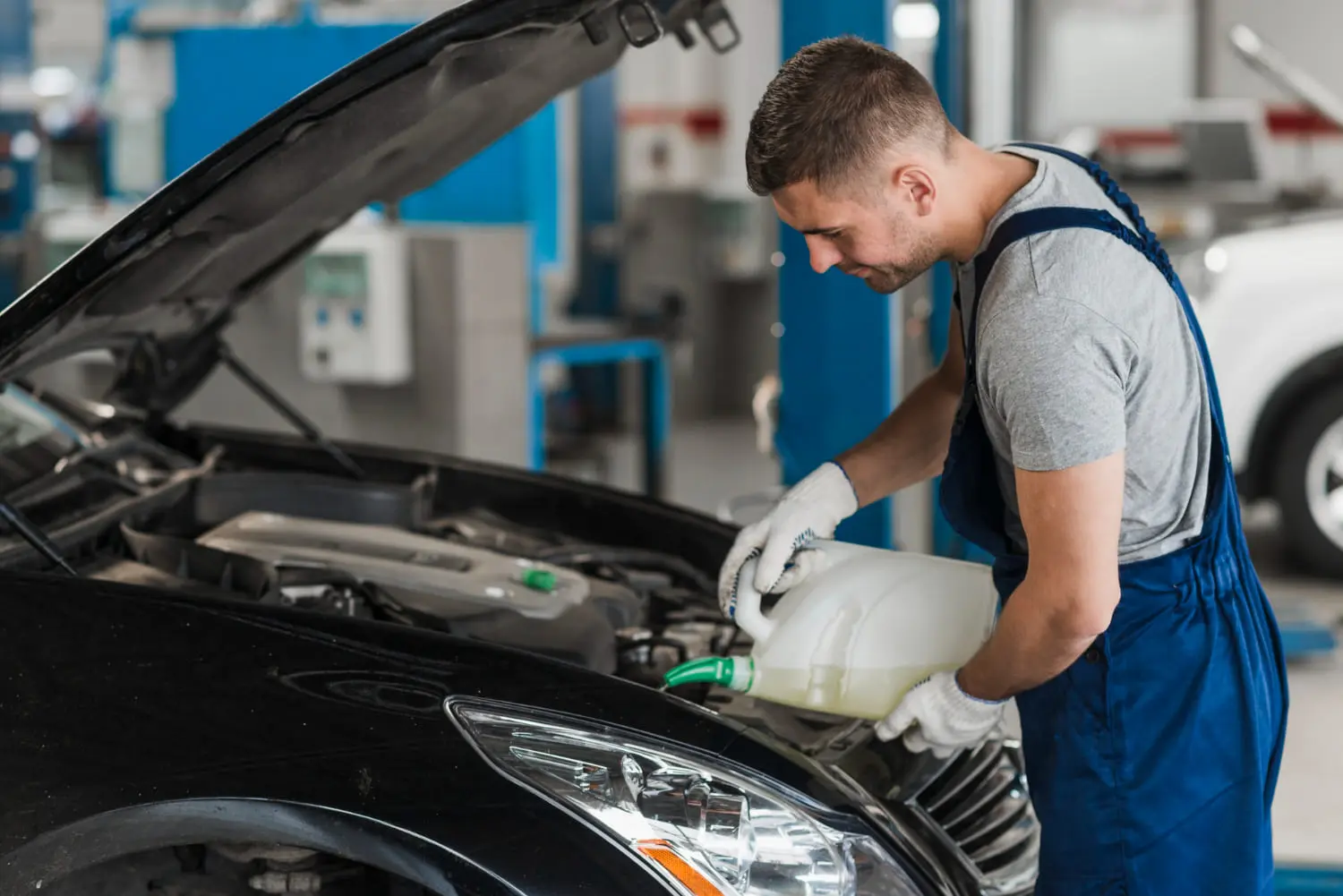 Mechanic pouring coolant into engine bay, showing when antifreeze needs a flush.