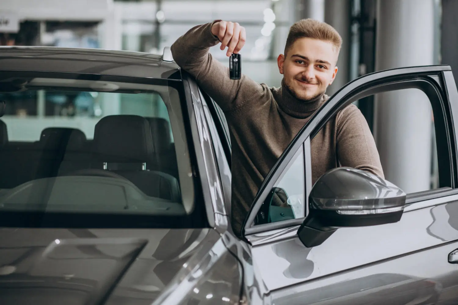 New driver holding car keys highlights choosing a safe, reliable first car today